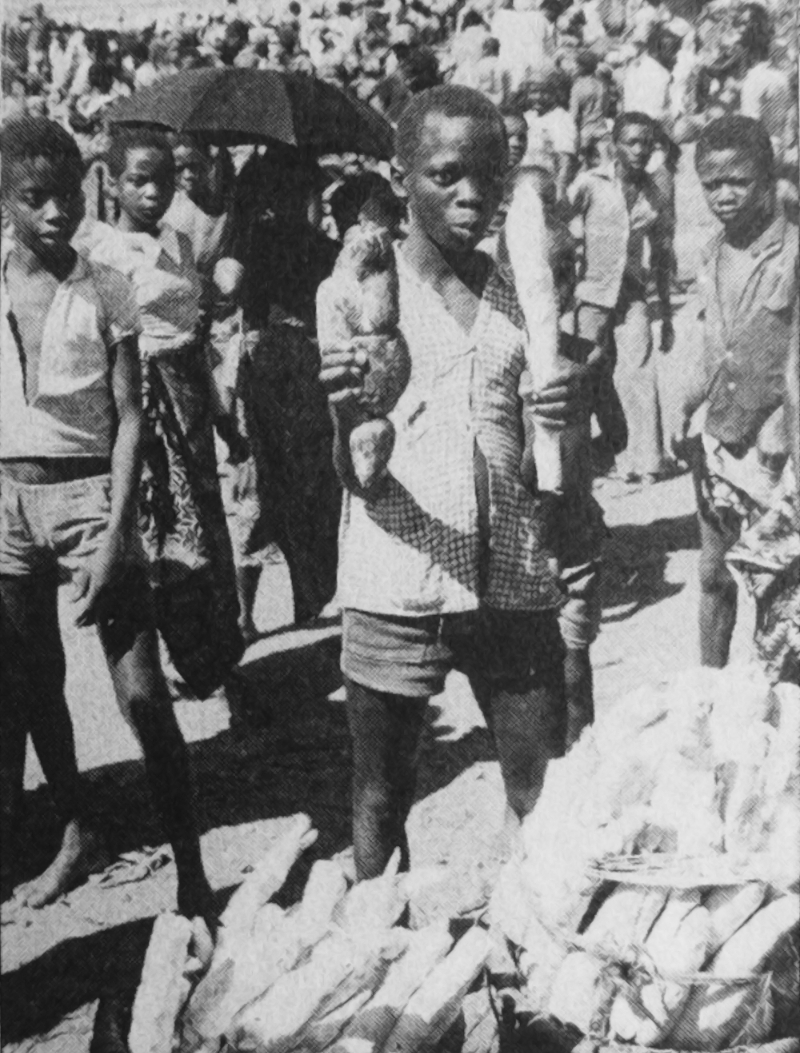 Blackened fermented peeled cassava root held by a boy in his right hand (left hand a boiled pod without fermentation), Tanganyka Lake - Ankei 1996